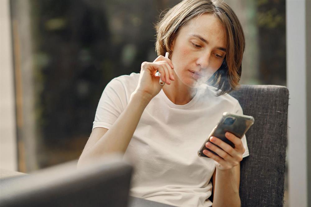 Woman with phone vaping